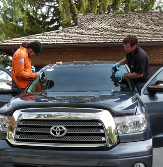 Photo of Ben and Jon replacing a cracked windshield. 